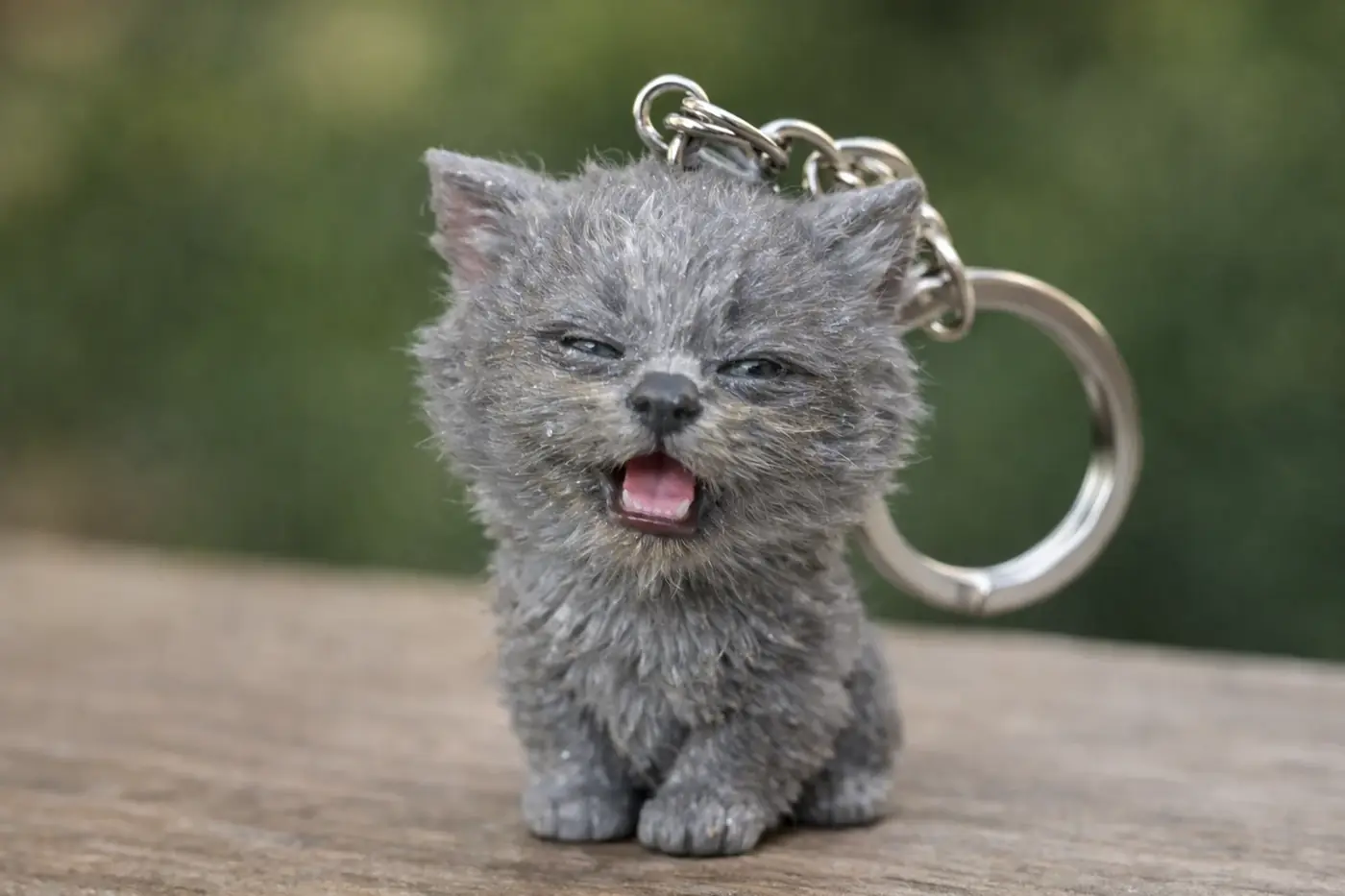 Miniature de chaton gris en porte-clé, avec expression espiègle et fond flou naturel.